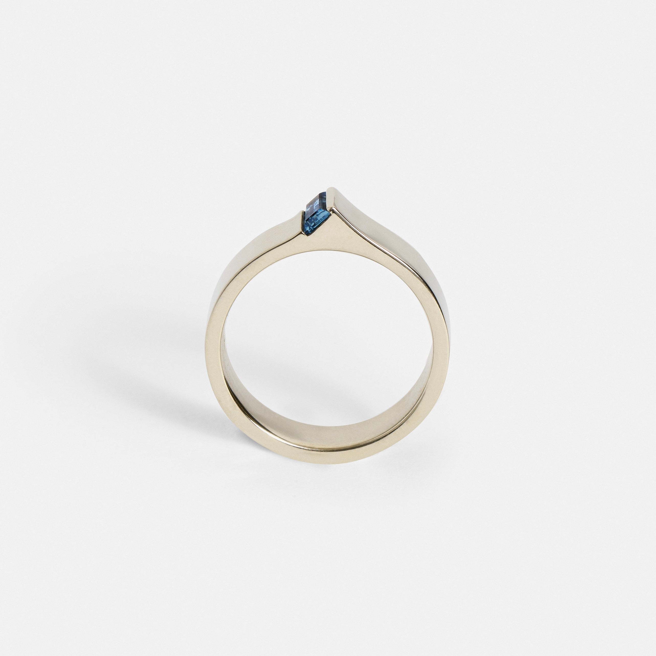 Wide white gold band showing exposed baguette sapphire from the side