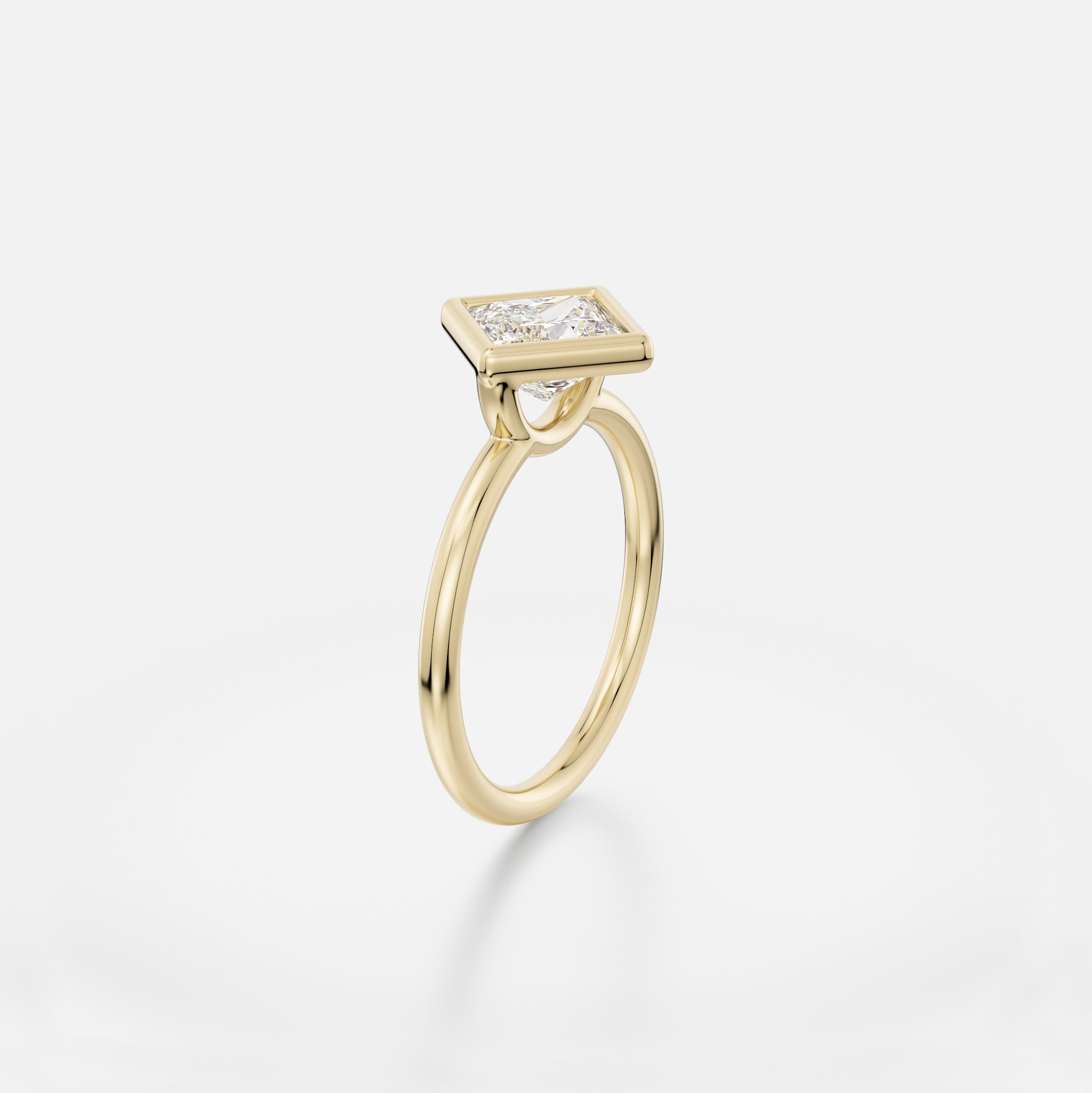 Delicate round profile band engagement ring with 1.5 ct princess diamond set at an angle in thin bezel