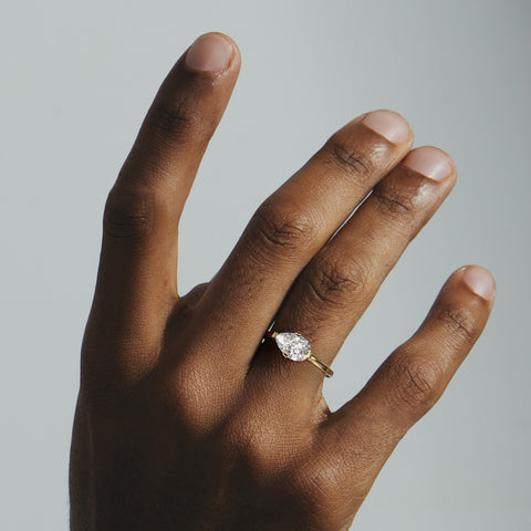 Close view of pear diamond set east west on thin flat gold band