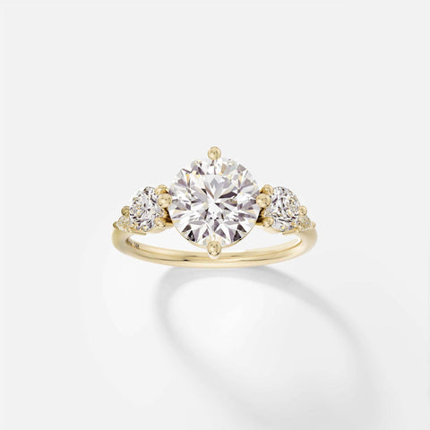 14k yellow gold five stone engagement ring with 2.50 carat round brilliant diamond and pear and round accent stones in compass prongs on delicate round band