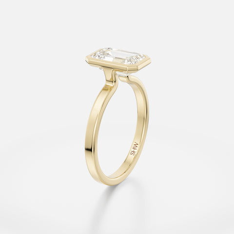 Delicate flat profile ring with thin bezel holding step-cut emerald diamond
