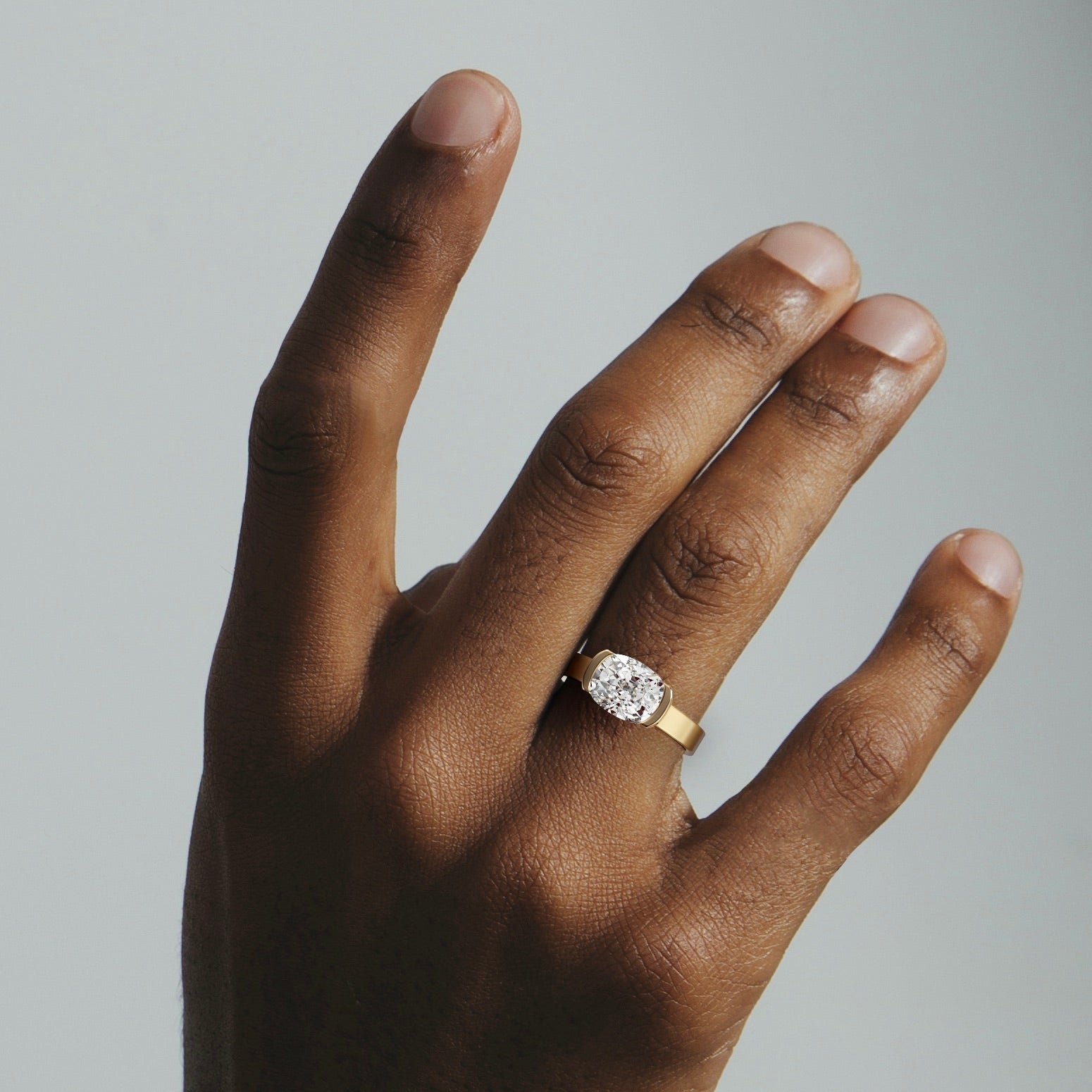 2.00 carat east-west cushion diamond engagement ring in tapered partial bezel worn on hand