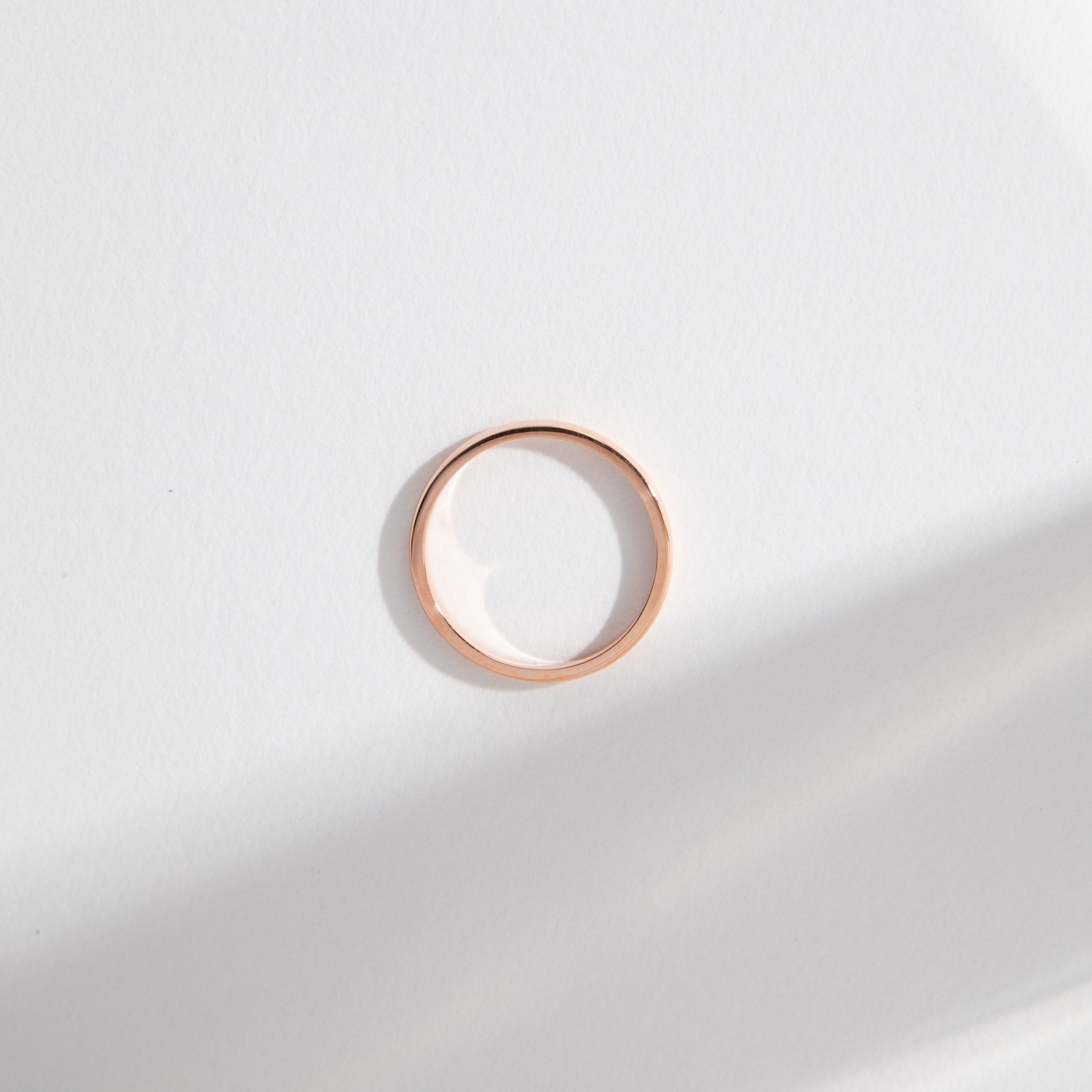 Side view of a slim domed wedding band in solid rose gold