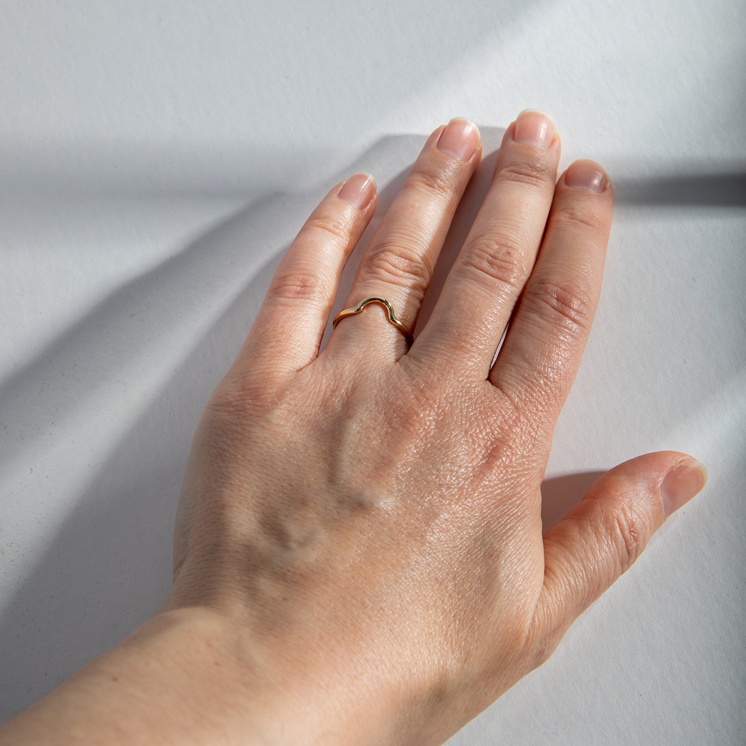 Thin round gold ring with curved detail worn on hand