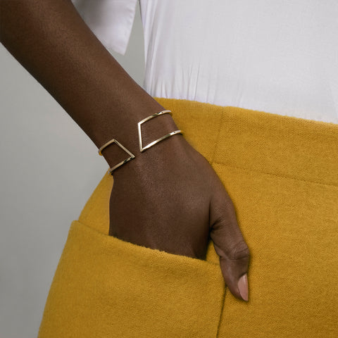 geometric yellow brass bracelet with angular design worn on wrist in natural light