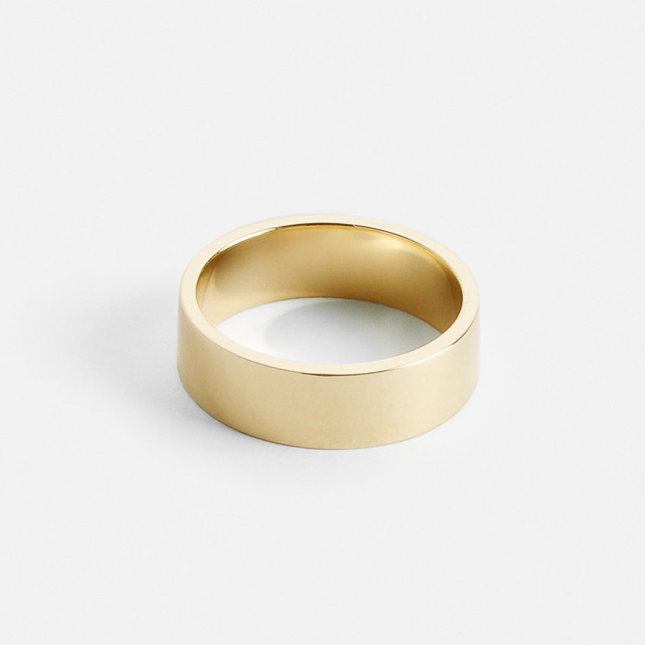 Close view of a wide flat gold wedding band with clean straight edges
