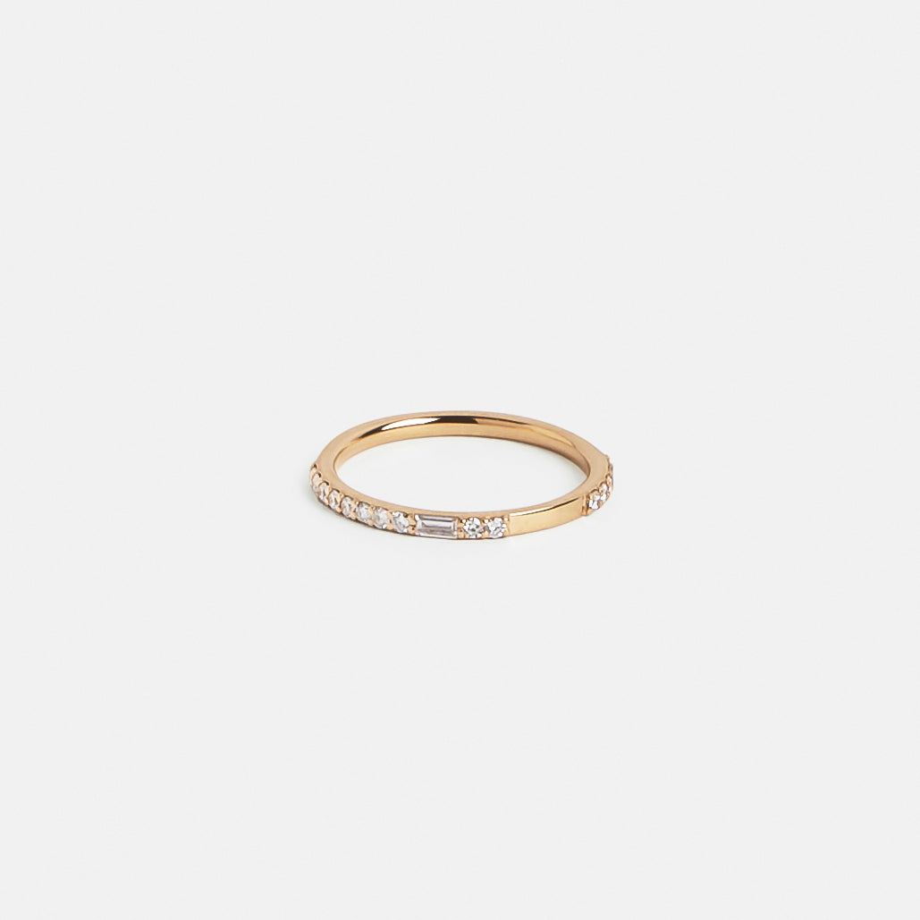 Slim gold band showing asymmetrical round and baguette diamond setting