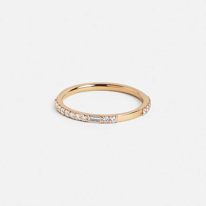 Close view of asymmetrical round and baguette white diamonds in a thin gold band