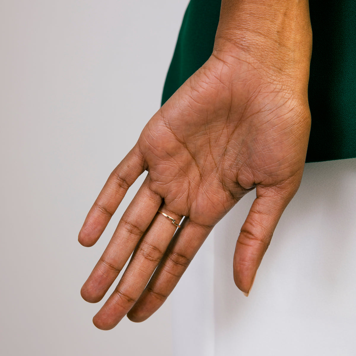 Thin gold diamond wedding band worn on model