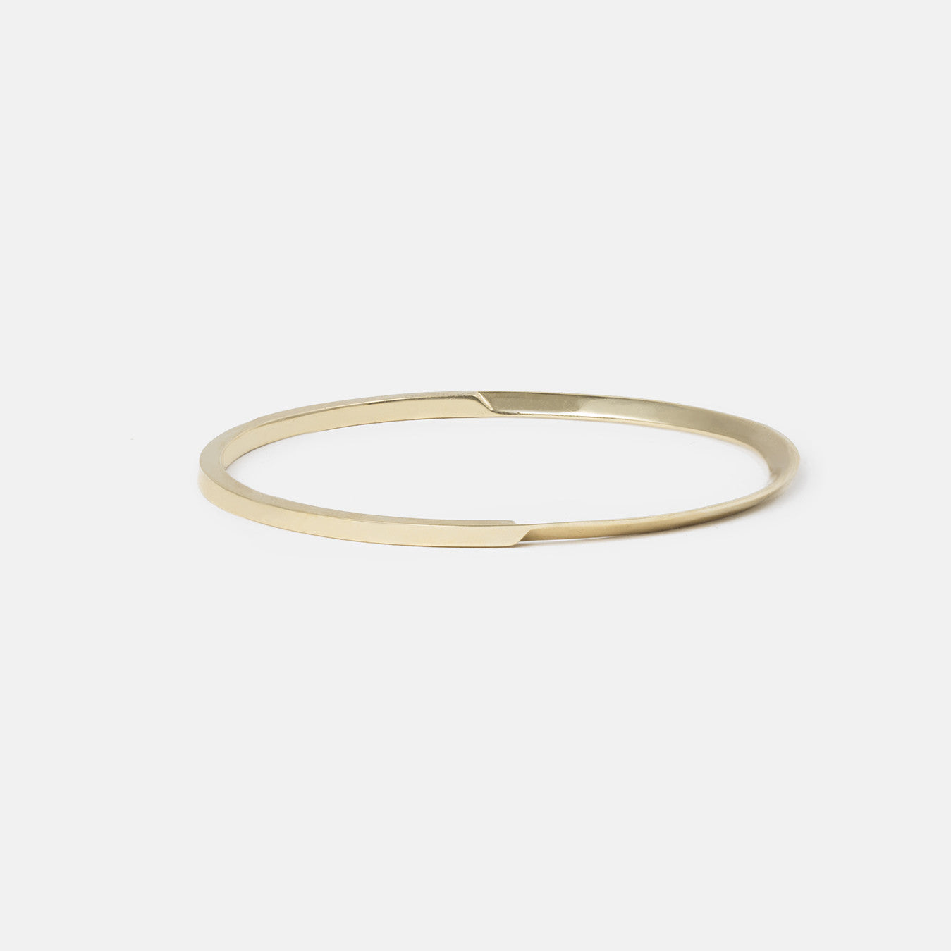 side profile of yellow brass bangle with curved tapered lines and angled structure
